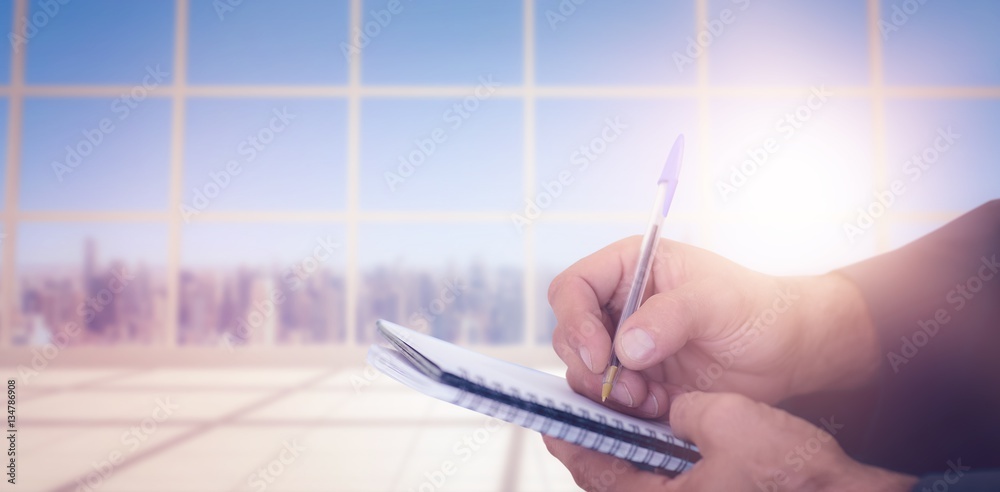 Composite image of close up of man writing in spiral book