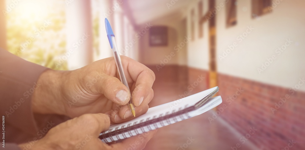 Composite image of close up of man writing in spiral book