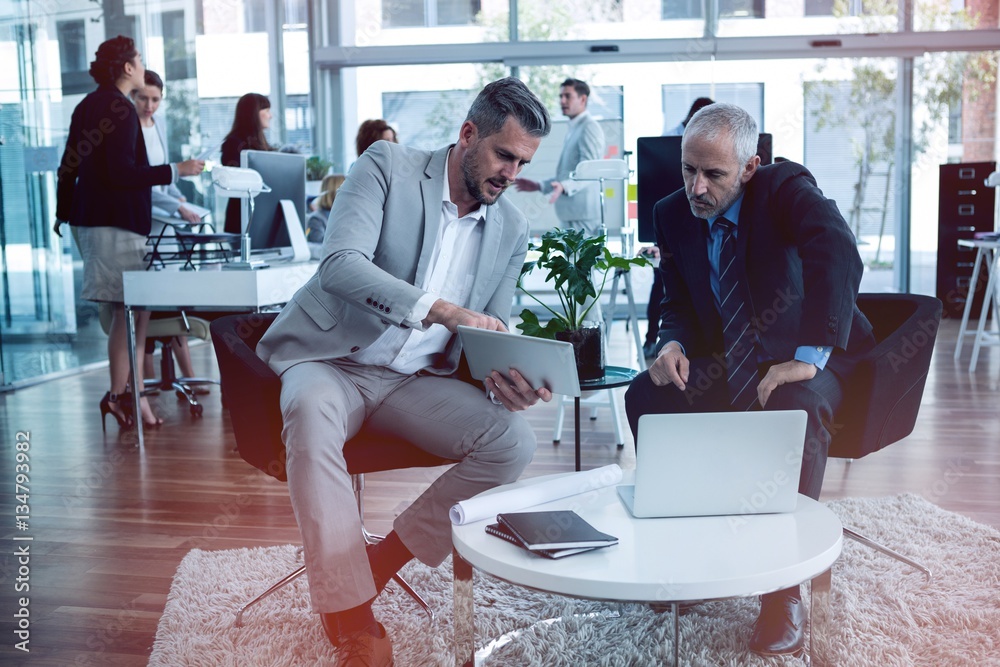 Businessmen discussing while using tablet