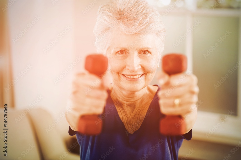 Portrait of senior woman exercising with dumbbells