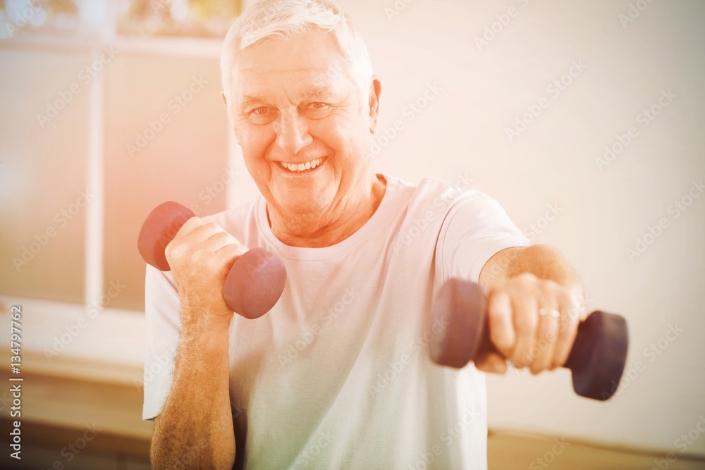 Portrait of senior man exercising with dumbbells