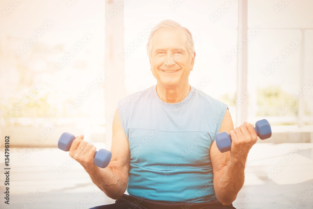 Portrait of senior man exercising with dumbbells