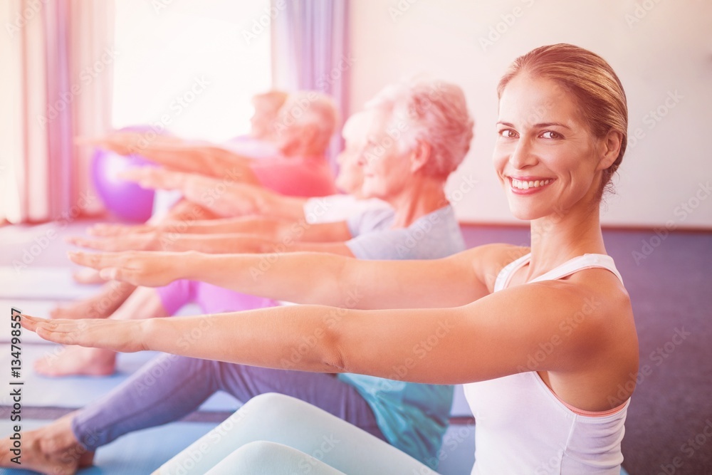 Portrait of Instructor performing yoga with seniors