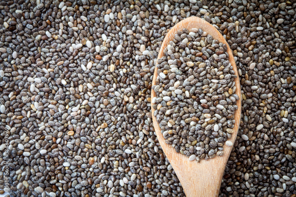 Close up chia seeds in wooden spoon on chia seeds background