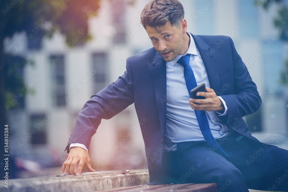 Stylish businessman using digital tablet on retaining wall