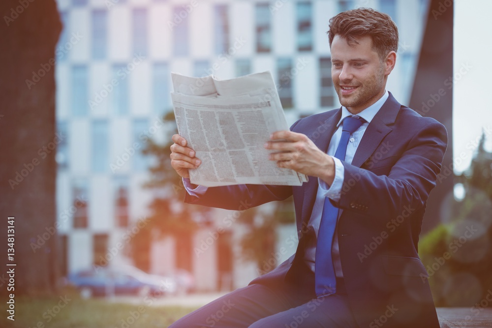 Happy businessman reading newspaper