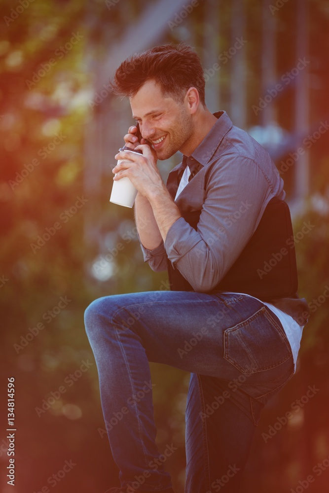 Handsome man talking on mobile phone and drinking coffee