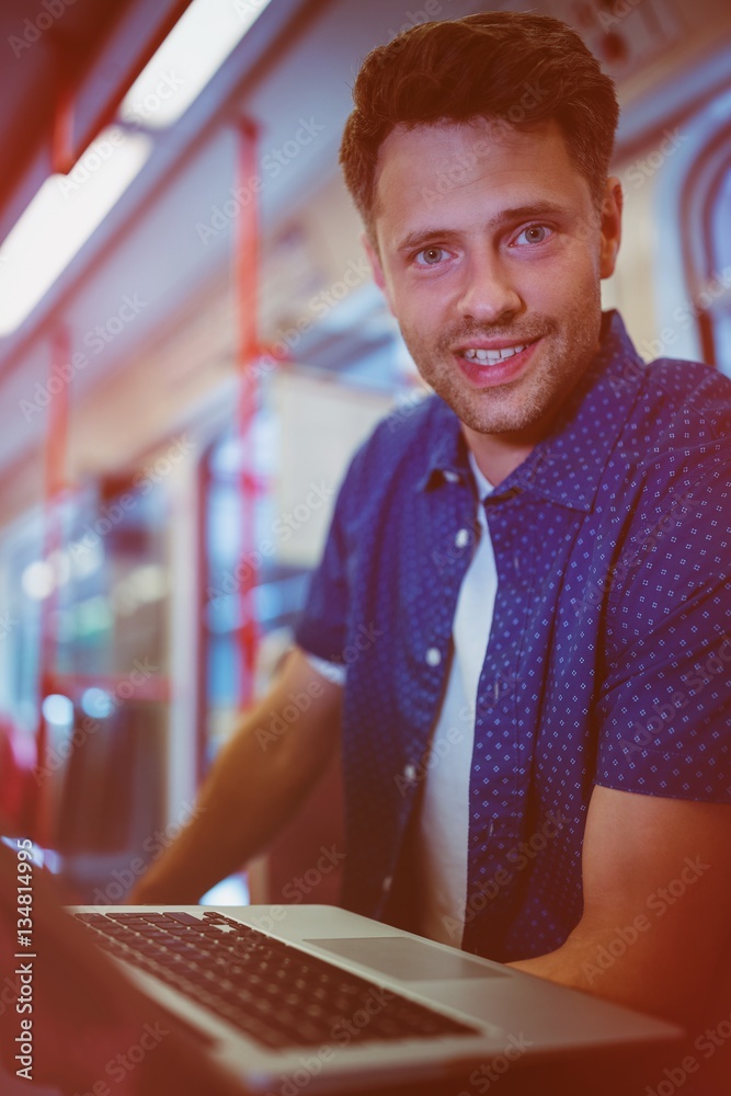 Portrait of handsome man using laptop in train