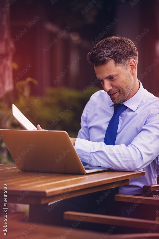 Happy businessman using laptop and digital tablet