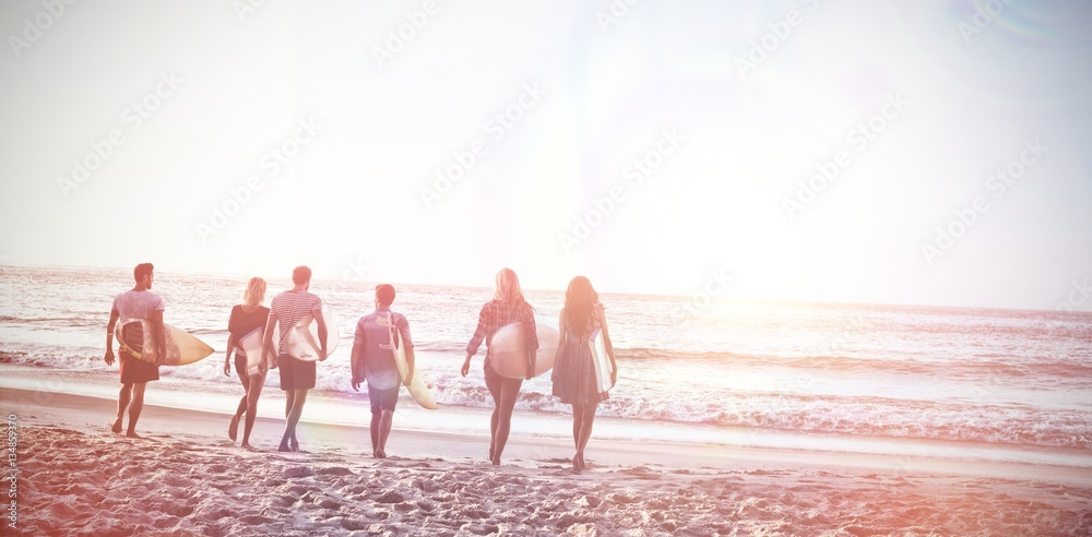 Happy friends walking with surfboards