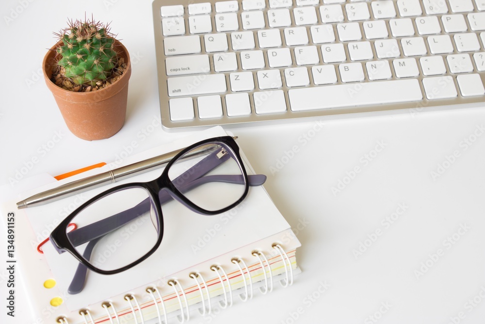 Office desk top view with copy space, eyeglasses and book. Office supplies Blank and notebook on whi