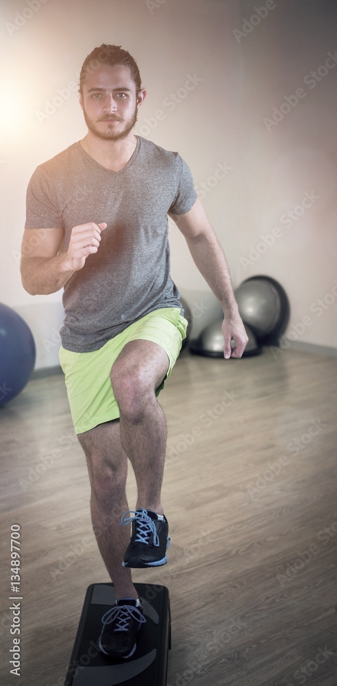 Portrait of serious man doing exercise on aerobic stepper 