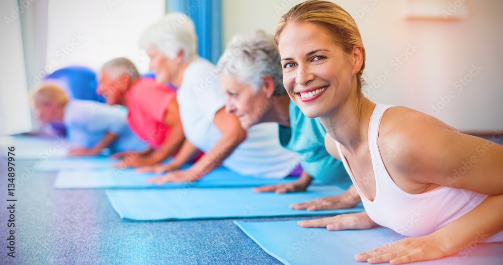 Portrait of instructor performing yoga with seniors