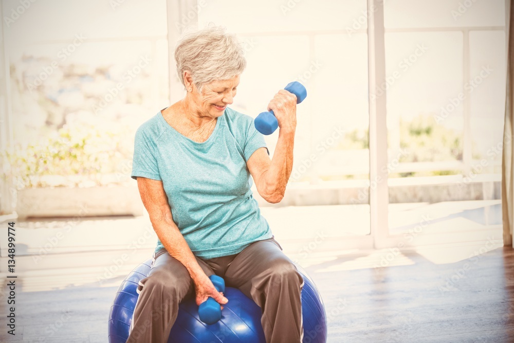 Smiling senior woman holding dumbbell