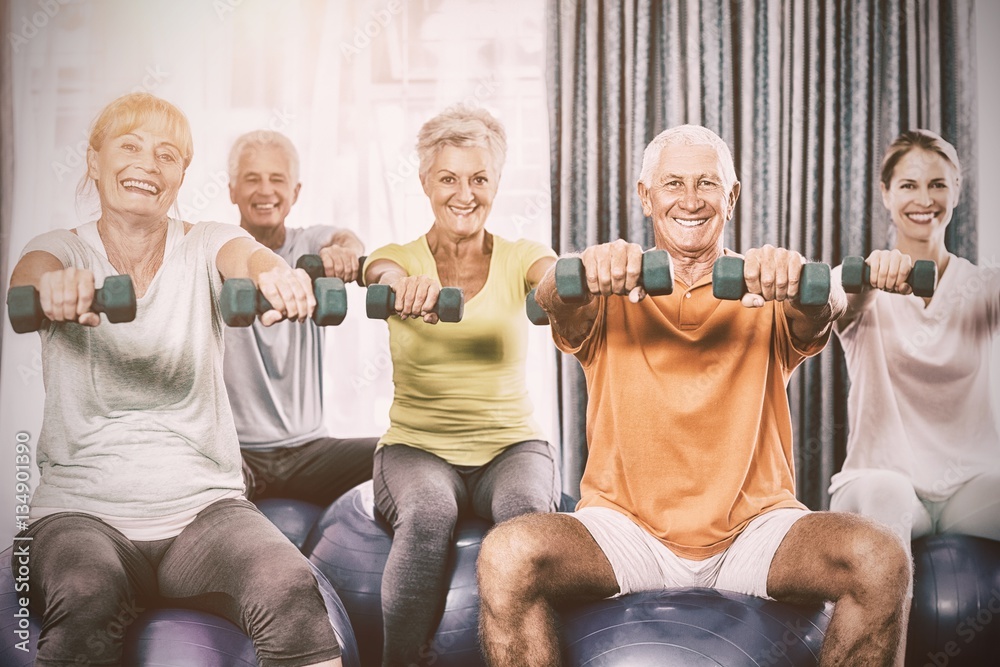 Portrait of seniors using exercise ball and weights