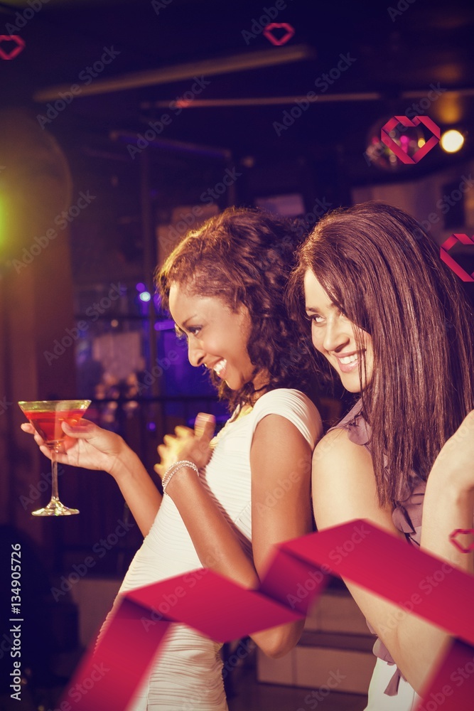 Composite image of happy young women having red cocktail