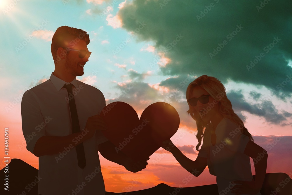 Composite image of cool young couple holding red heart