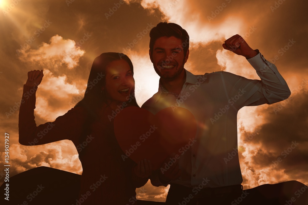 Composite image of cheerful couple holding paper heart