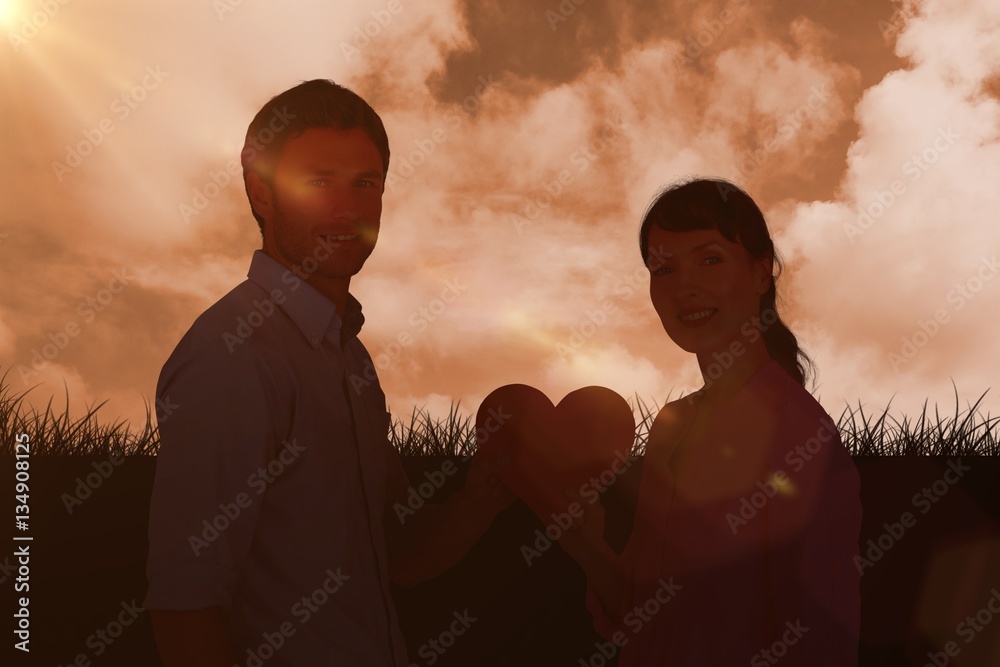 Composite image of couple holding a red heart