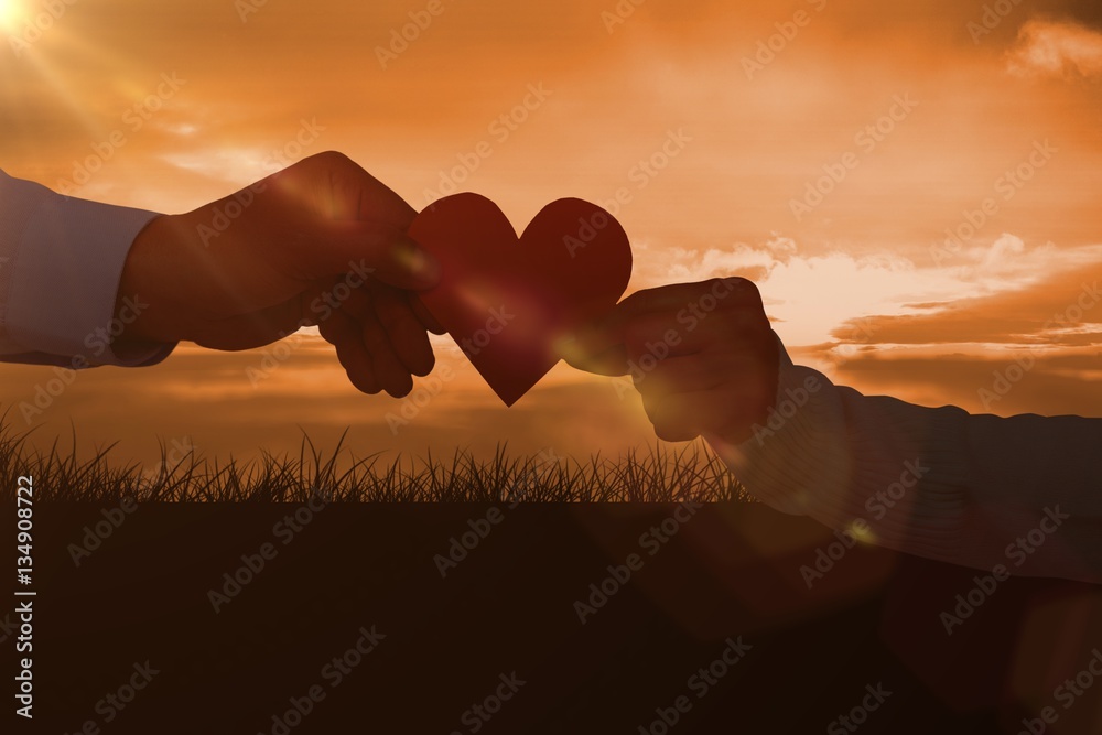 Composite image of couple holding paper heart shape paper