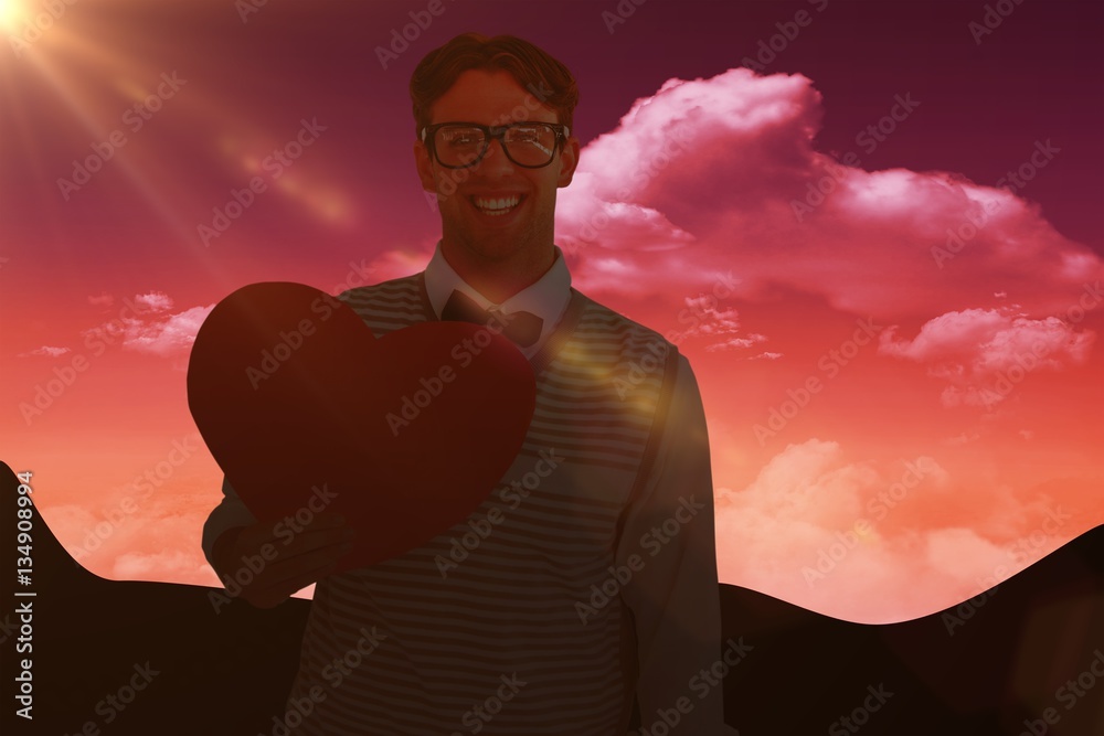 Composite image of geeky hipster holding heart card