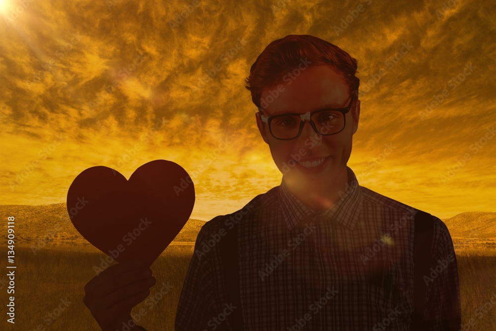 Composite image of geeky hipster holding a heart card