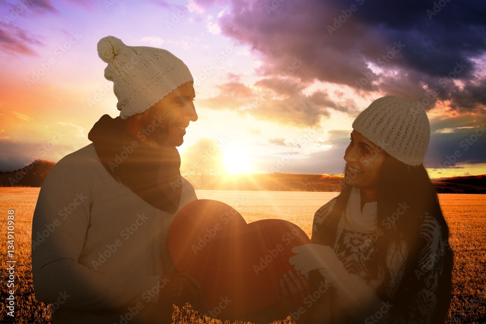 Composite image of smiling couple holding paper heart