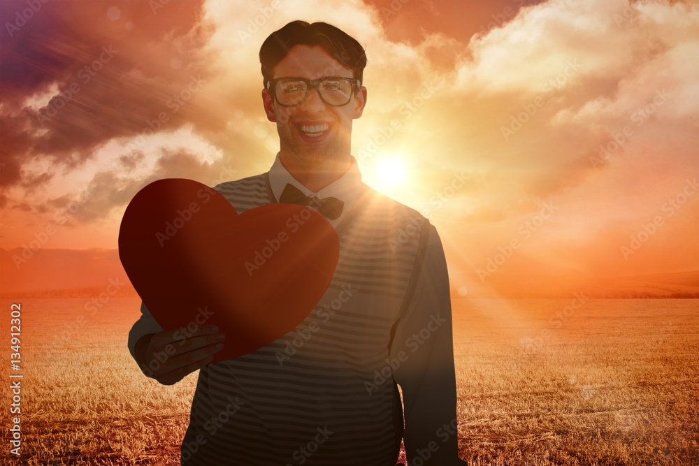 Composite image of geeky hipster holding heart card