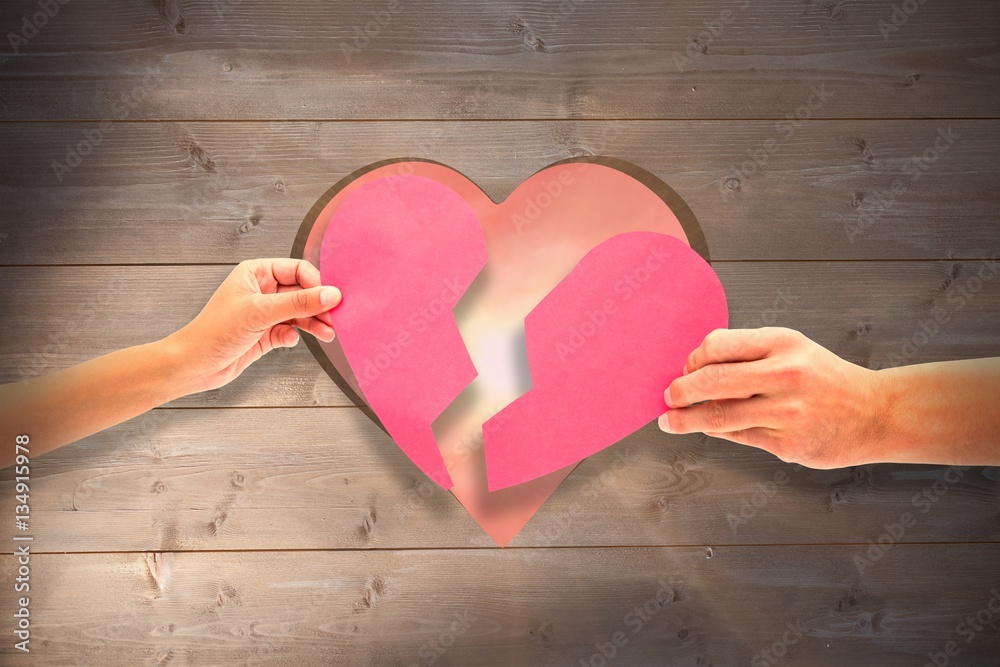 Composite image of hands holding two halves of broken heart