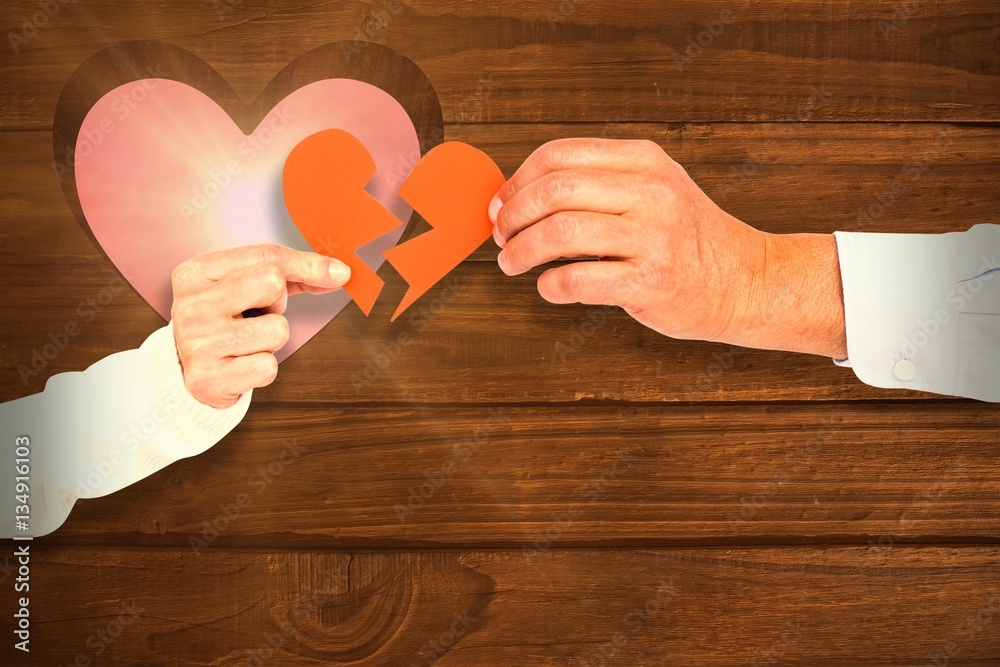 Composite image of couple holding broken heart shape paper