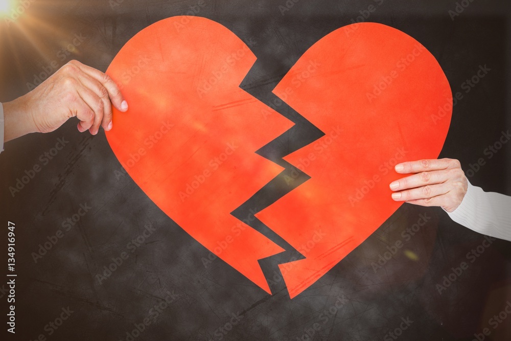 Composite image of couple holding broken heart shape paper