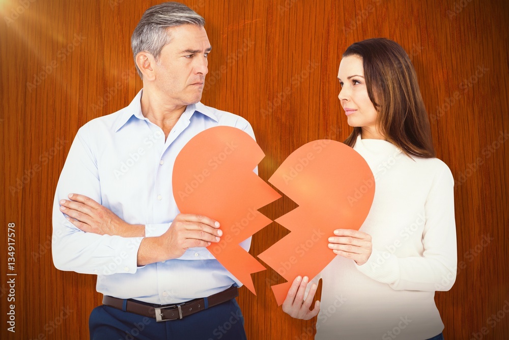 Composite image of couple holding broken heart shape paper