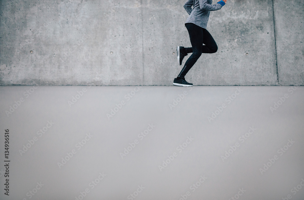 Female runner running on gray background