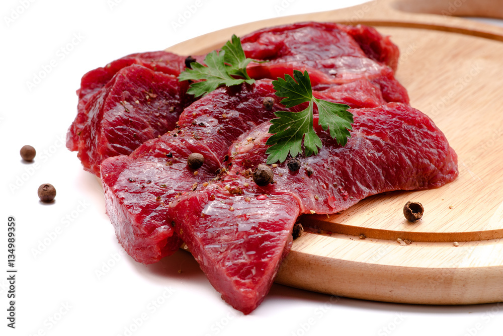 Pieces of meat with garlic and parsley on wooden board isolated. Raw beef.