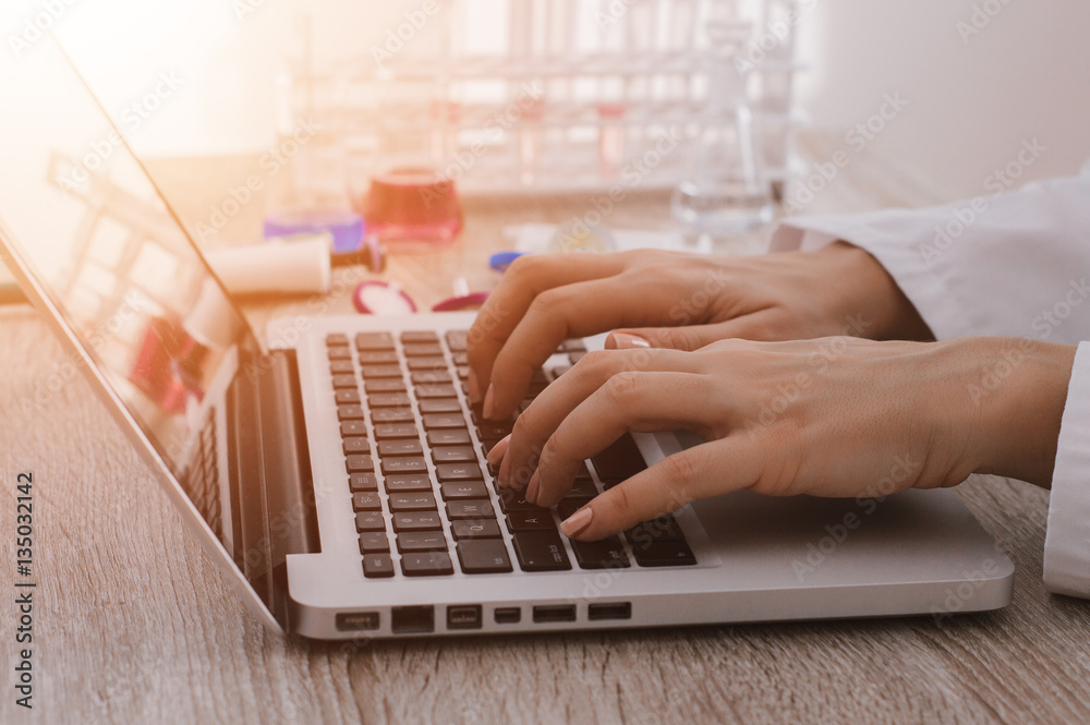 Researcher working at desk and typing on a keyboard, lens flare