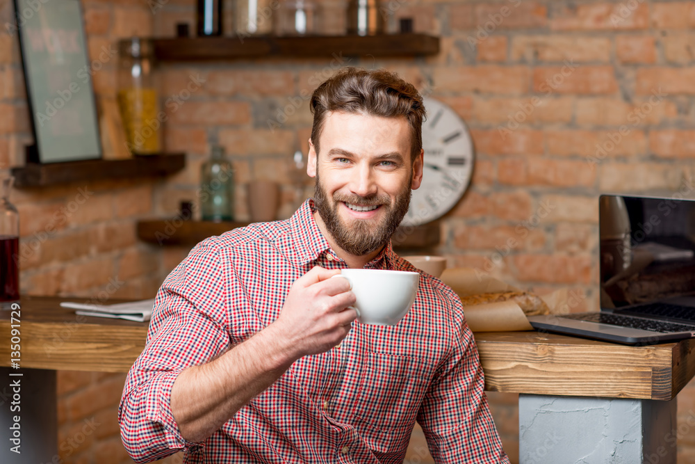 Handsome man drinking coffee at the kitchen