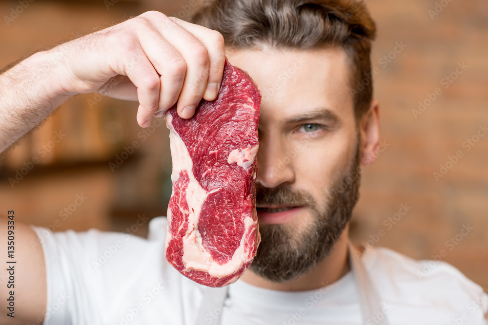 Close-up portrait of a handsome man with raw meat hiding his face