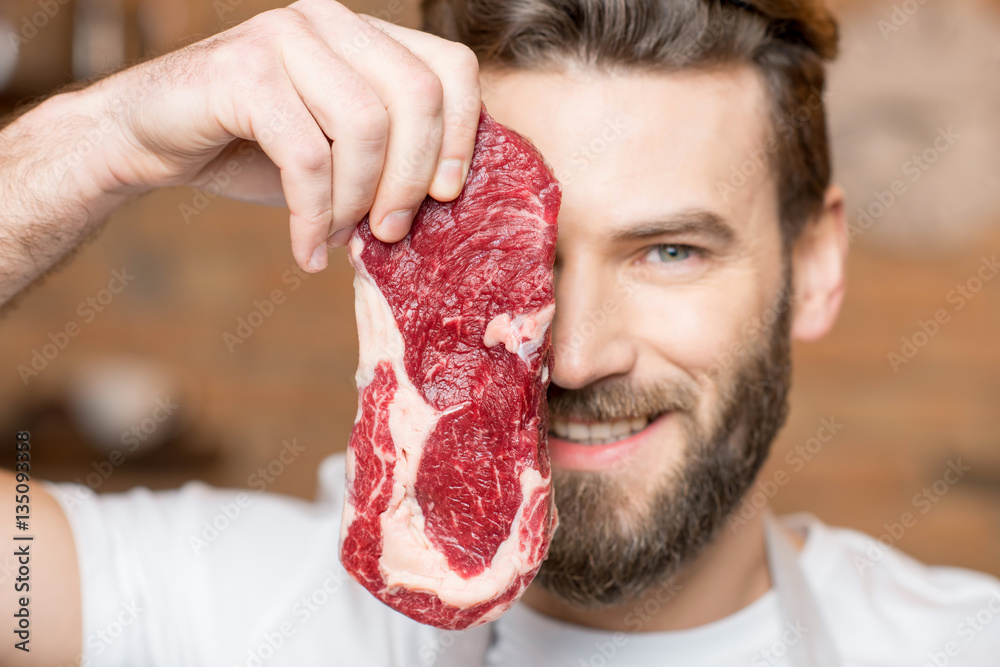 Close-up portrait of a handsome man with raw meat hiding his face