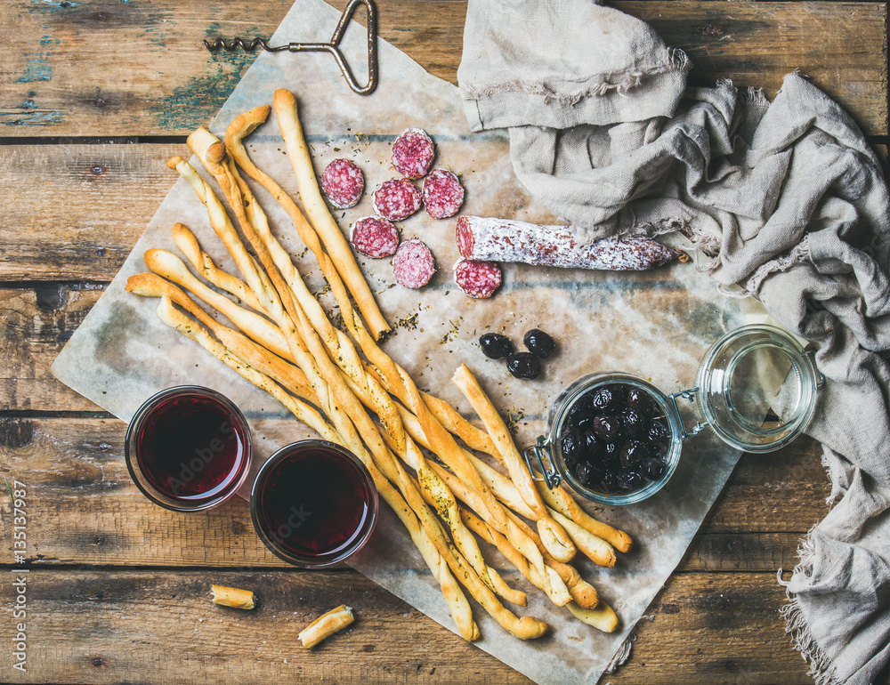 Wine and appetizers set. Italian Grissini bread sticks, dry cured pork meat sausage, black olives in