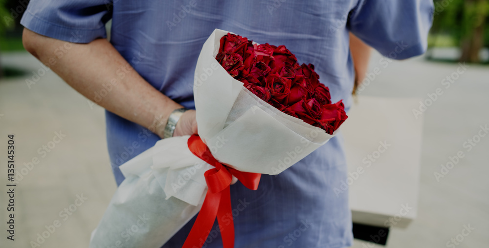 Guy hiding a bouquet of flowers behind his back