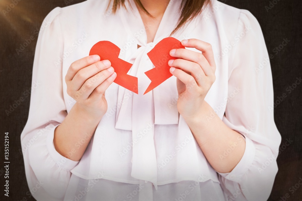 Composite image of woman holding broken heart paper