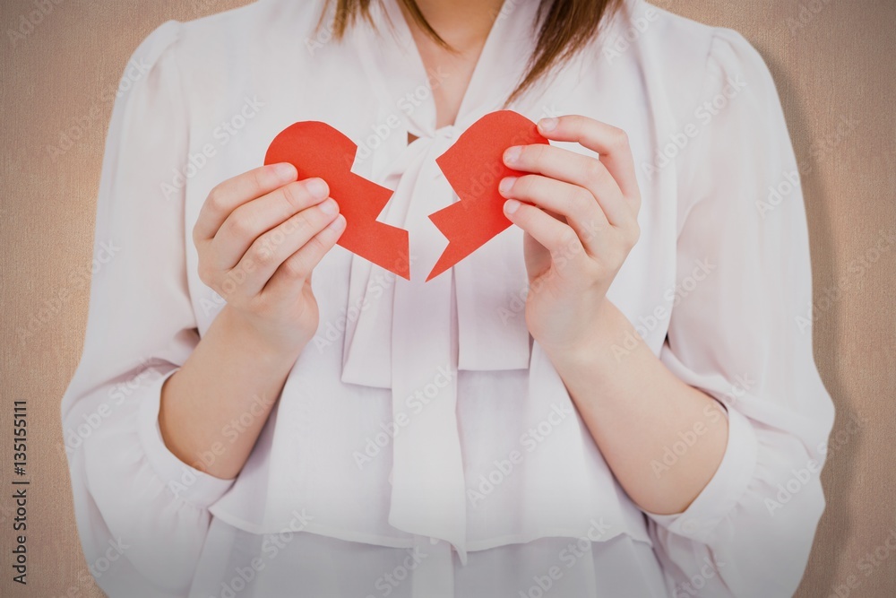 Composite image of woman holding broken heart paper