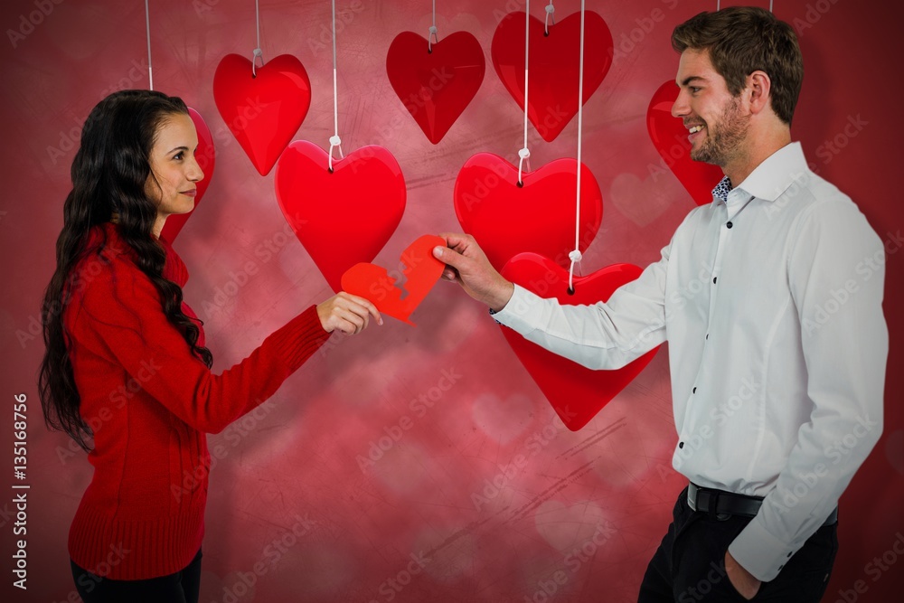 Composite image of couple holding red cracked heart shape 3d