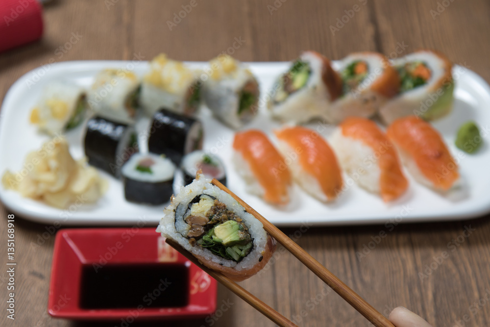 Sushi Set rolls with salmon and maki served on white plate on wooden table