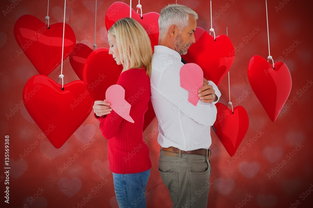 Composite image of couple holding two halves of broken heart 3d