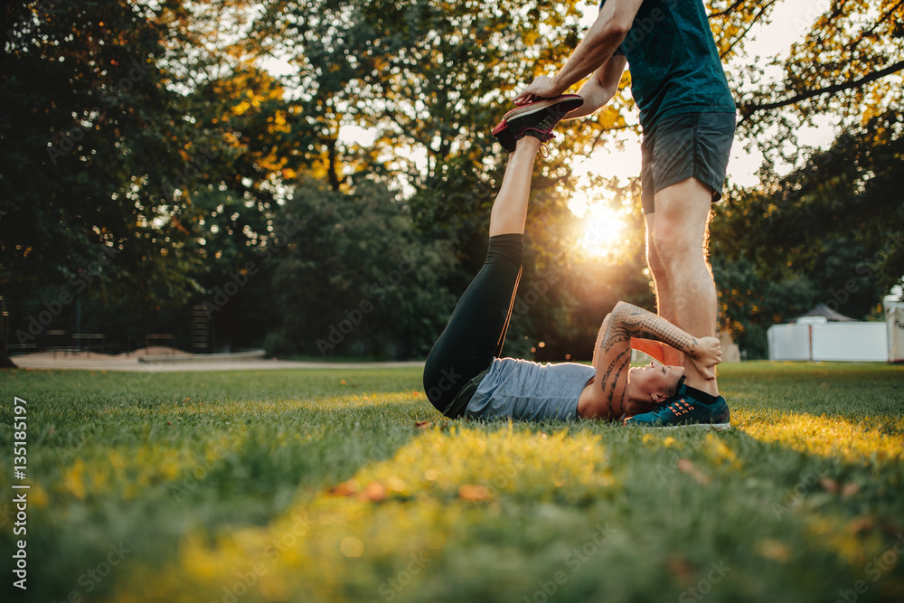 Personal trainer assisting woman in leg stretching workout