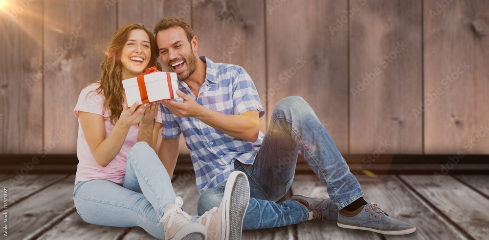 Composite image of happy young couple holding gift