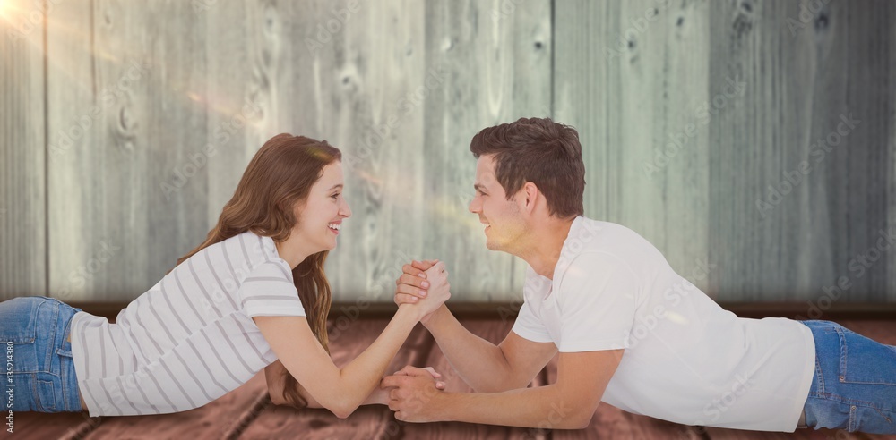 Composite image of happy couple arm wrestling 