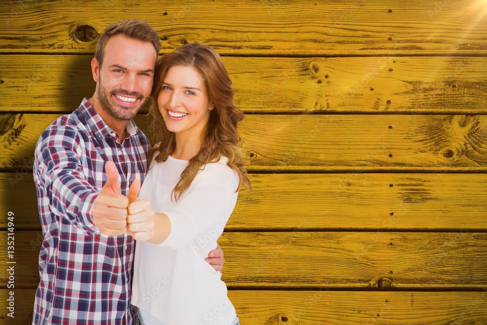 Composite image of happy young couple putting thumbs up