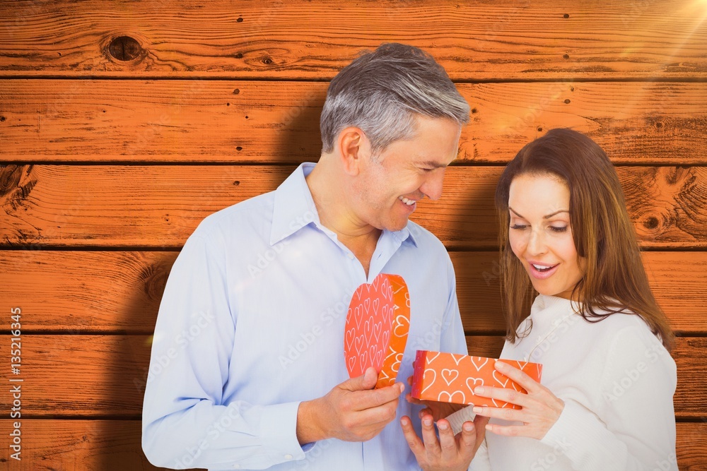 Composite image of happy couple opening present